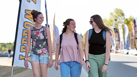 Three students walking in front of residence hall.